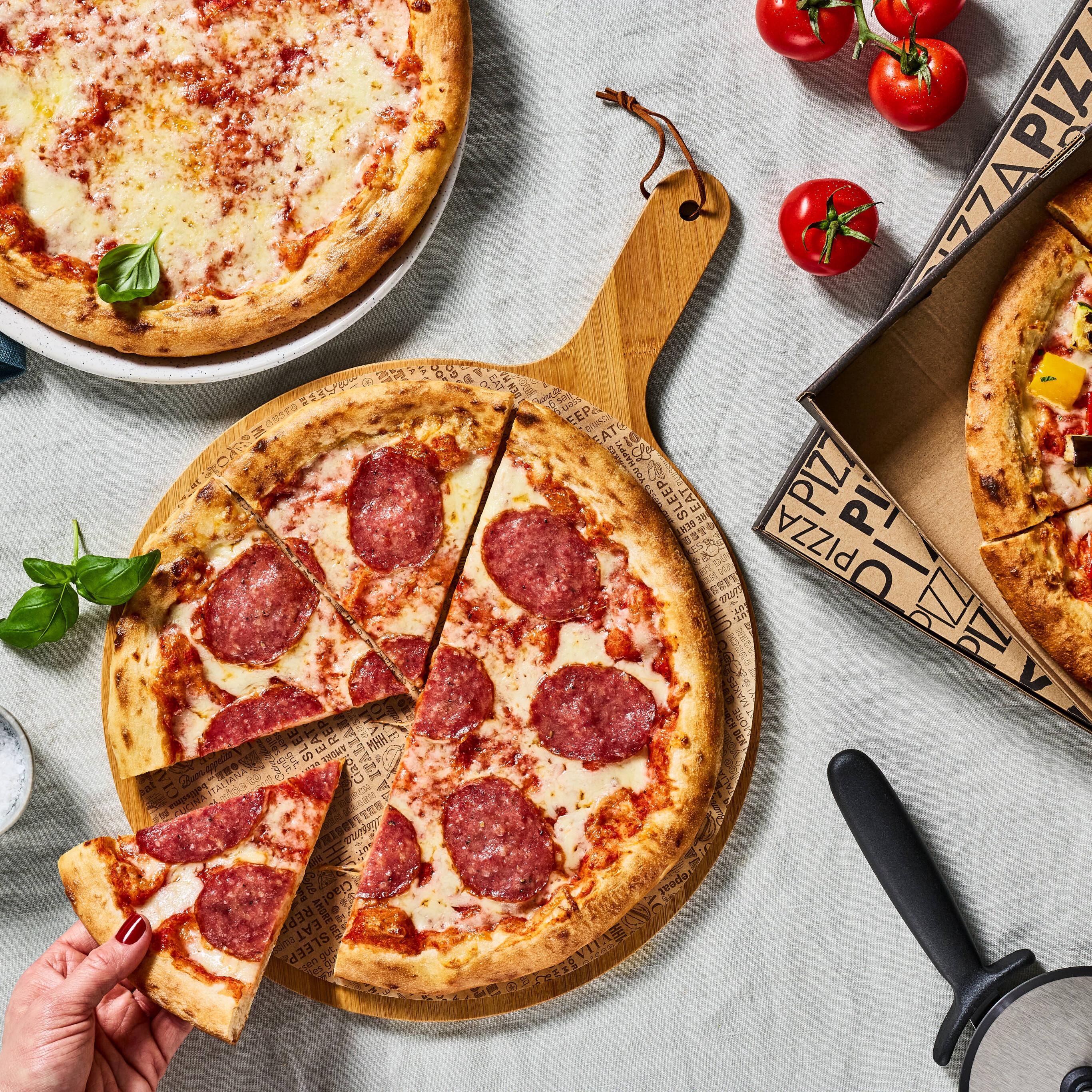 Eine Hand nimmt ein Stück Pizza von einem Pizzabrett.