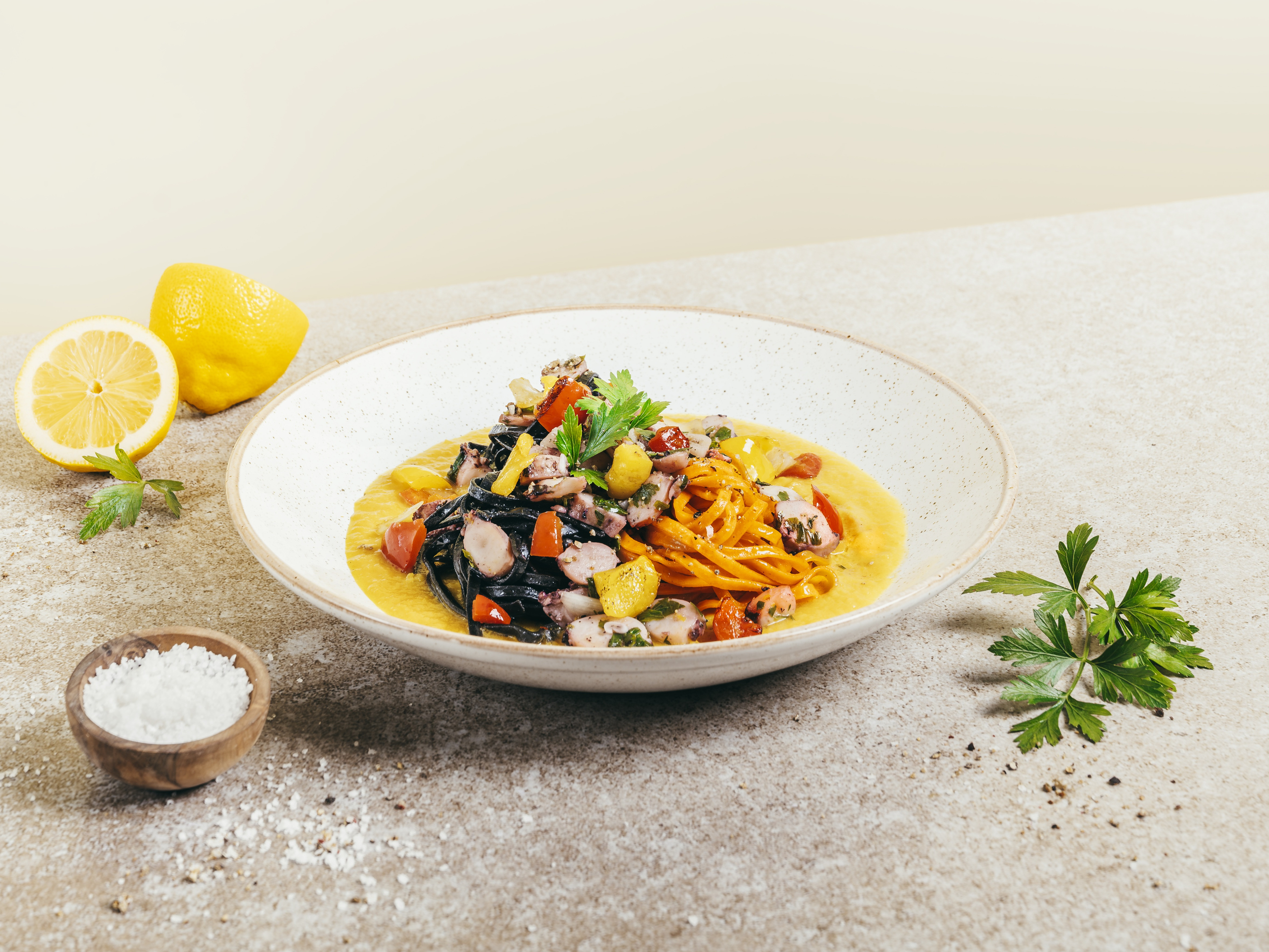 Pasta Español von Salva D'Or Ein Teller mit Nudeln und Tintenfischscheiben auf einem Tisch.