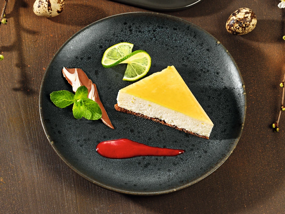 Das Sortiment umfasst eine Auswahl hochwertiger Dessertkreationen, die mit sorgfältig ausgewählten Zutaten, fein abgestimmten Rezepturen und einer ansprechenden Präsentation überzeugen. Ein Teller mit Gebäck und eine Tasse Kaffee.