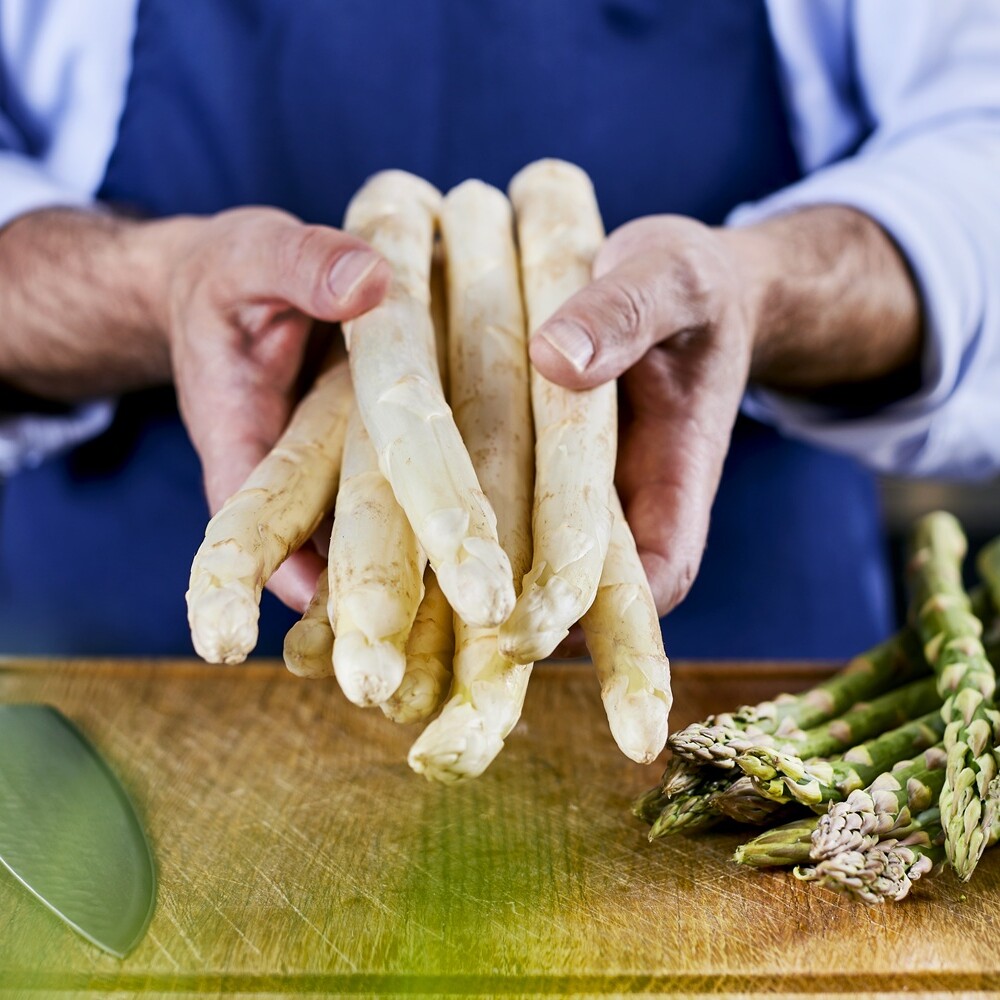Eine Person hält ein Bündel Spargel.