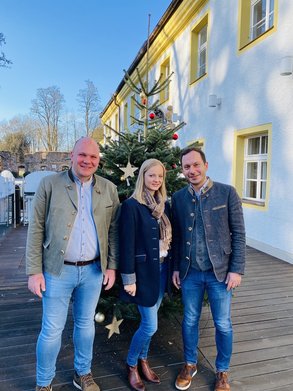 Daniel, Kerstin und Martin Vrbnjak Eine Gruppe von Menschen steht vor einem Weihnachtsbaum.