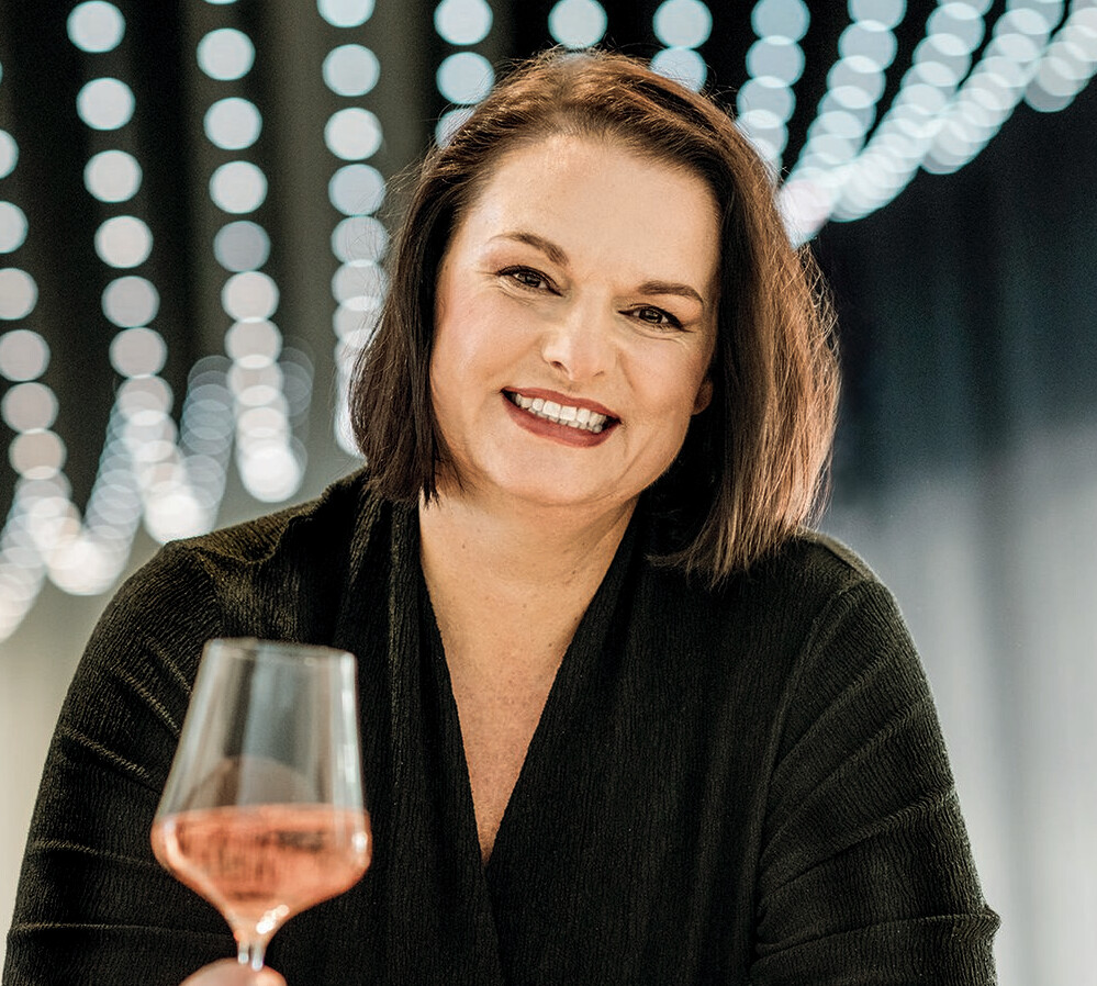 Maja Kirsch Frau hält ein Weinglas in der Hand und lächelt.