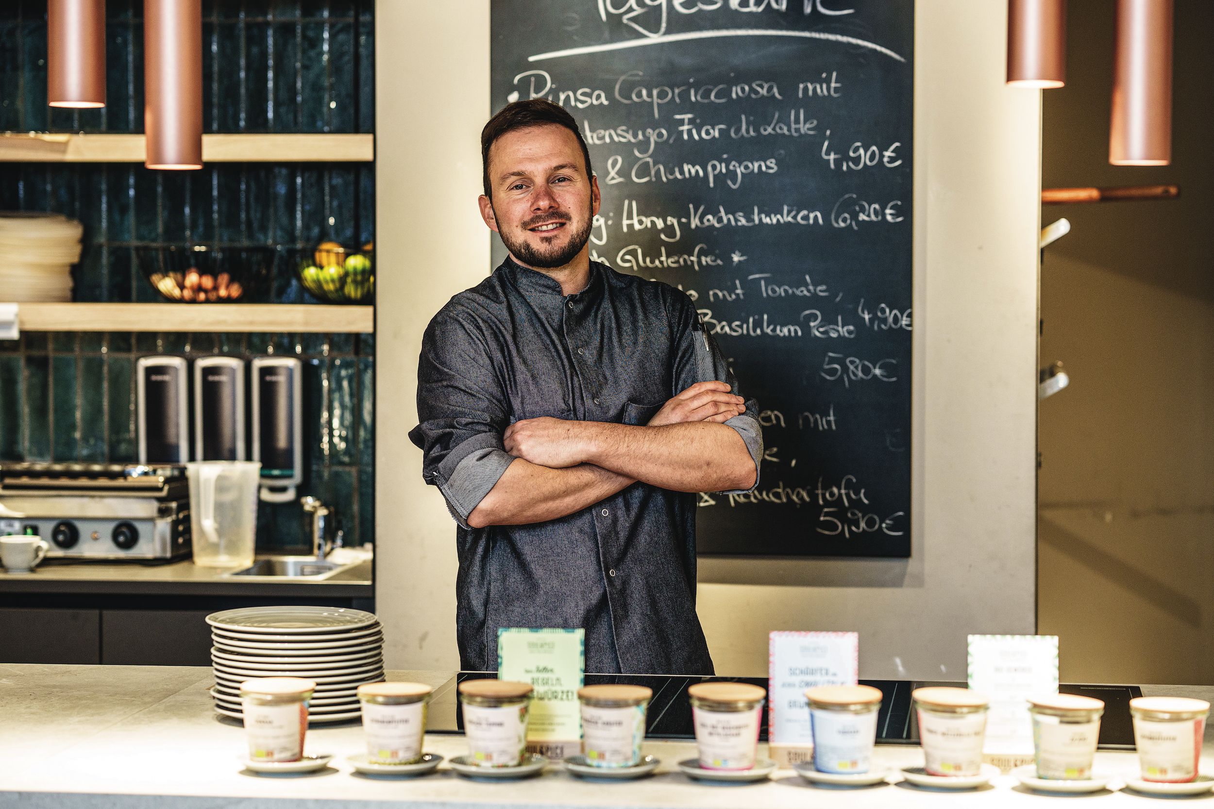 Küchenchef Philipp Kögel Ein Mann steht vor einer Tafel.