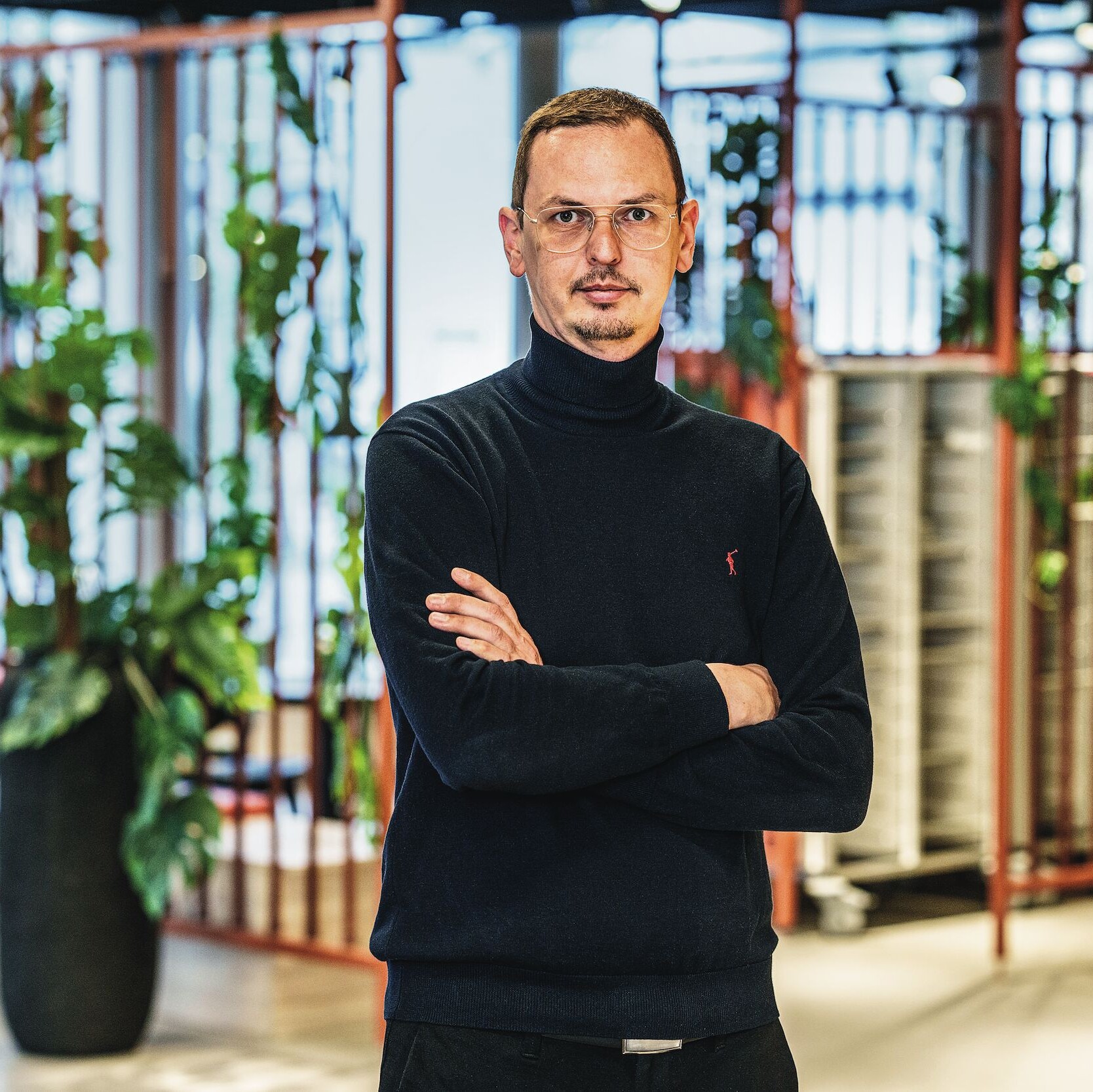 Alexander Thiel Ein Mann mit Brille und Rollkragenpullover lächelt.