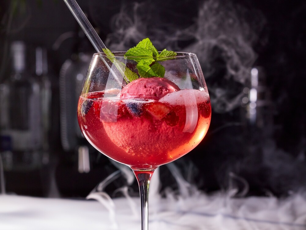 Better Desserts Berry Spritz Ein Glas mit einem Cocktail und einer Fruchtgarnitur.
