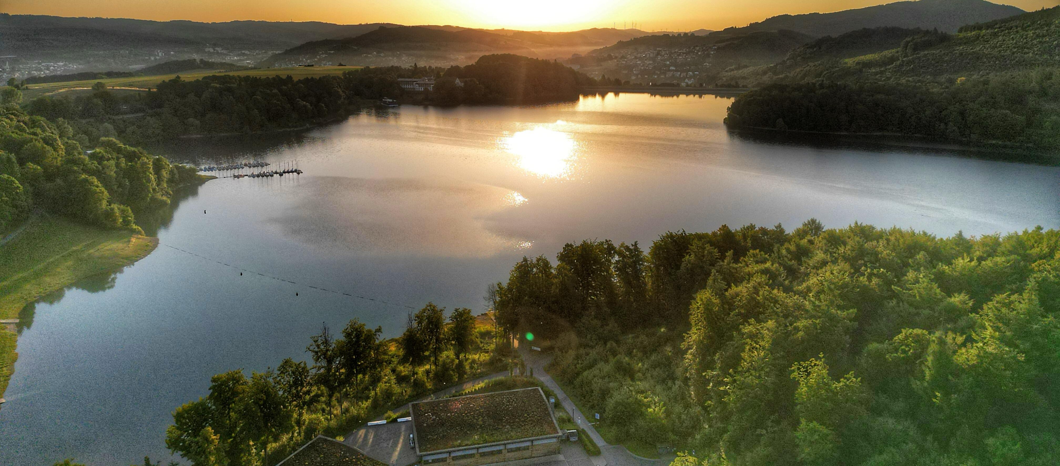 Ein See, umgeben von Bäumen und Gebäuden.