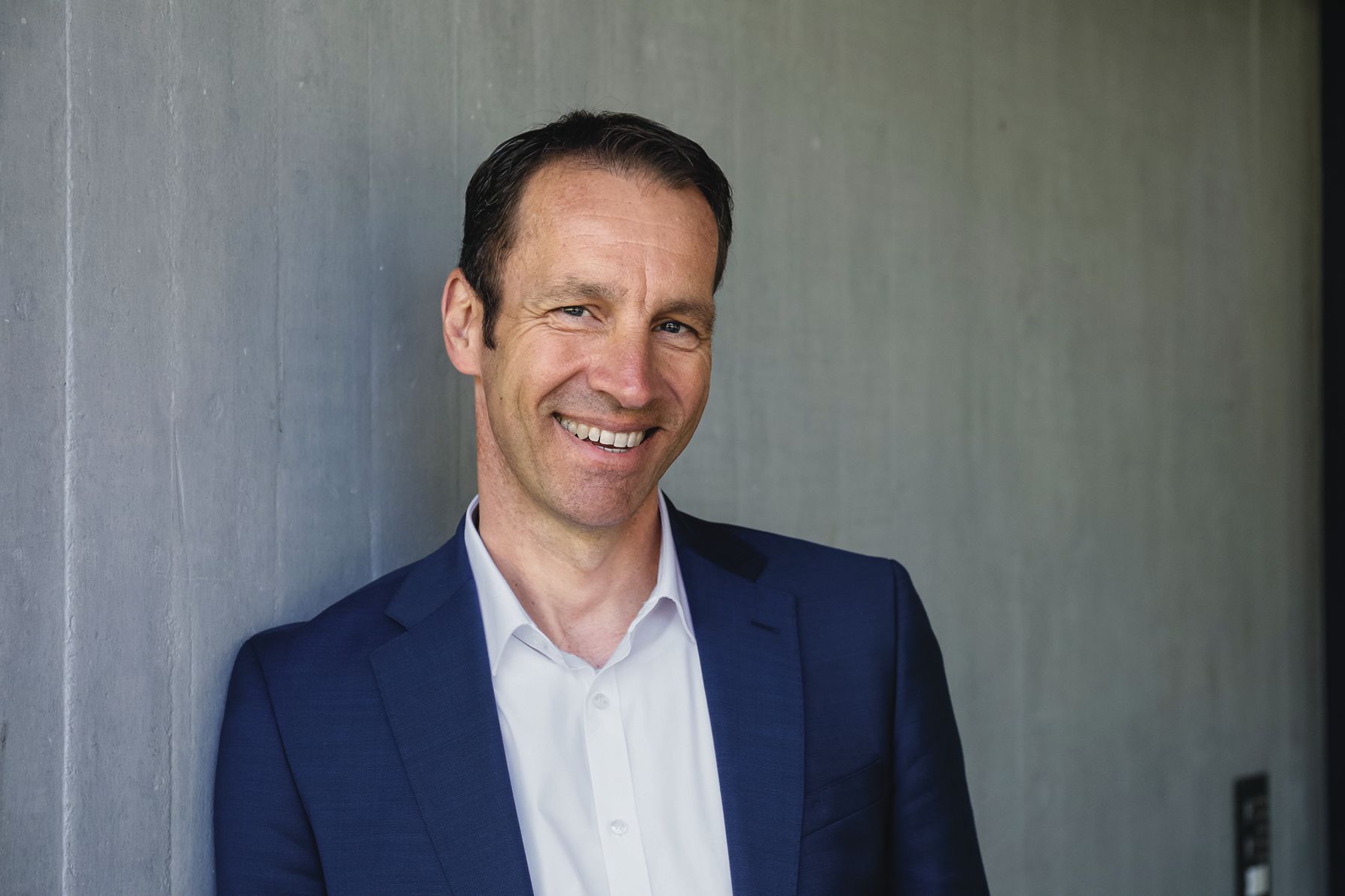 Ein Mann im Anzug lächelt.