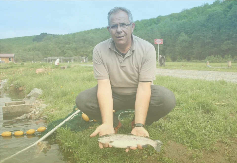 Forellenzucht Hochspessart Ein Mann hält einen Fisch.