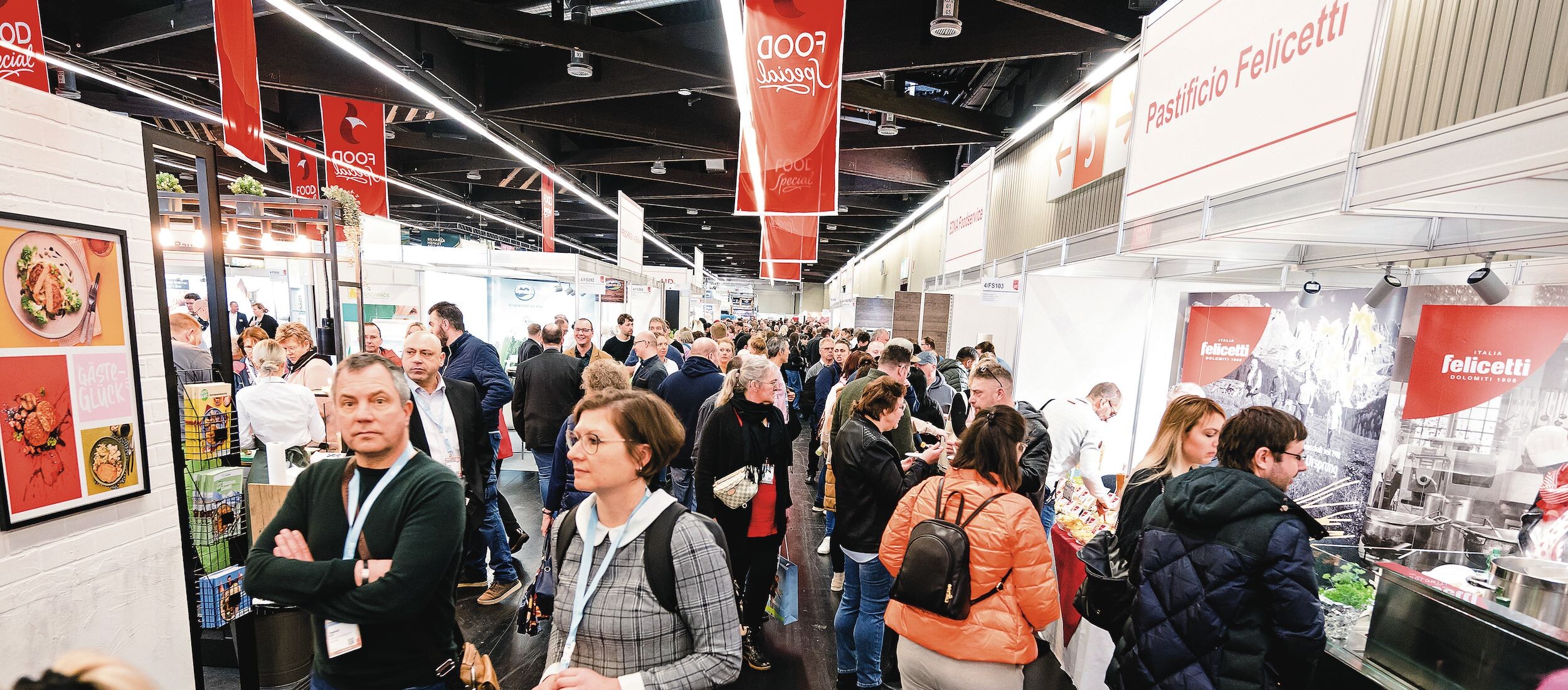 Eine Gruppe von Menschen in einem Raum, darunter Männer und Frauen, die stehen und miteinander interagieren.