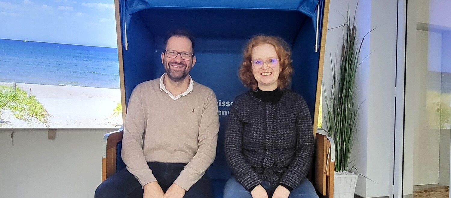 Ein Mann und eine Frau sitzen lächelnd in einem Strandkorb.