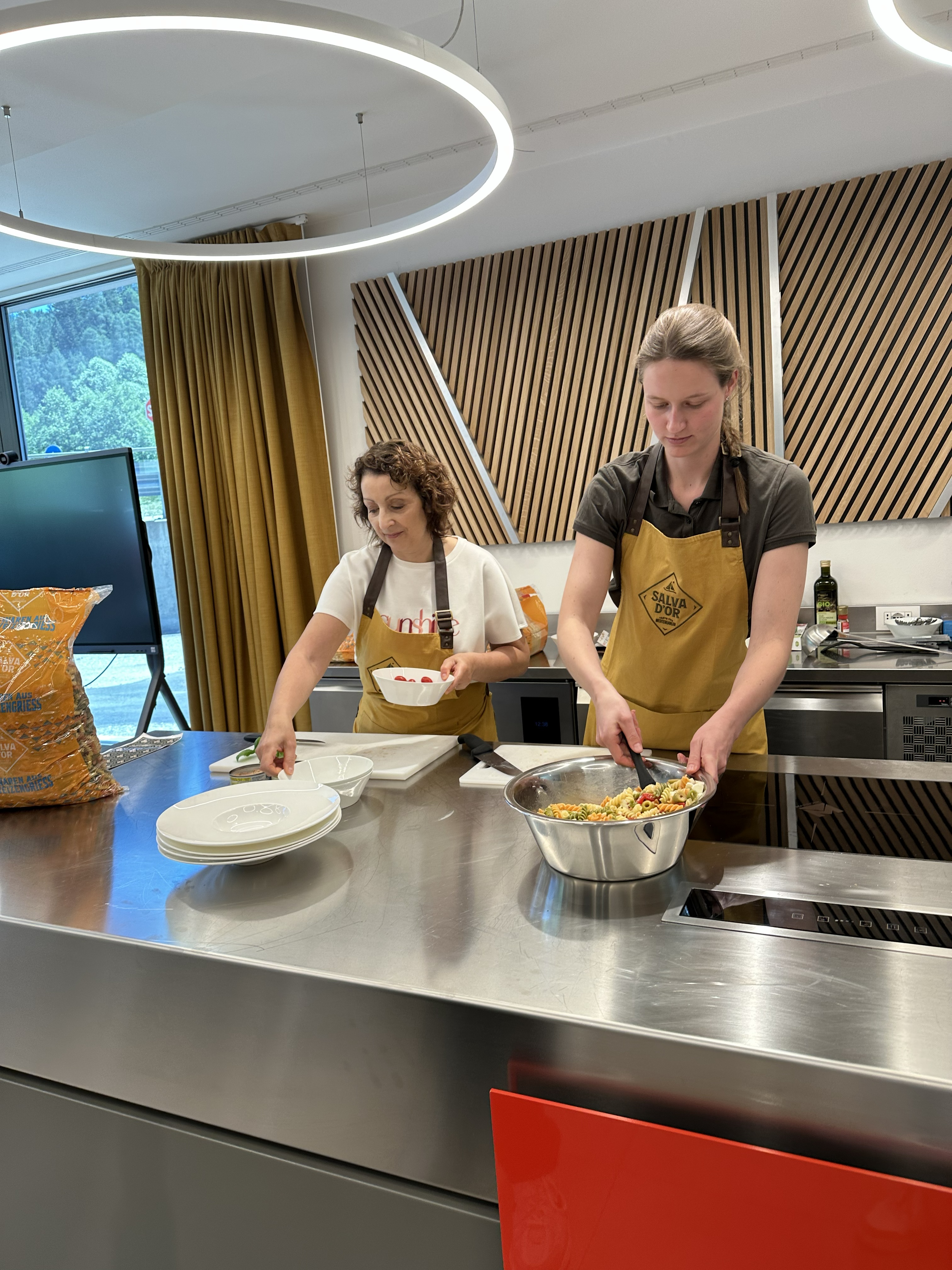 Pasta kochen in den Dolomiten Zwei Frauen in Schürzen bereiten in einer Küche Essen zu.