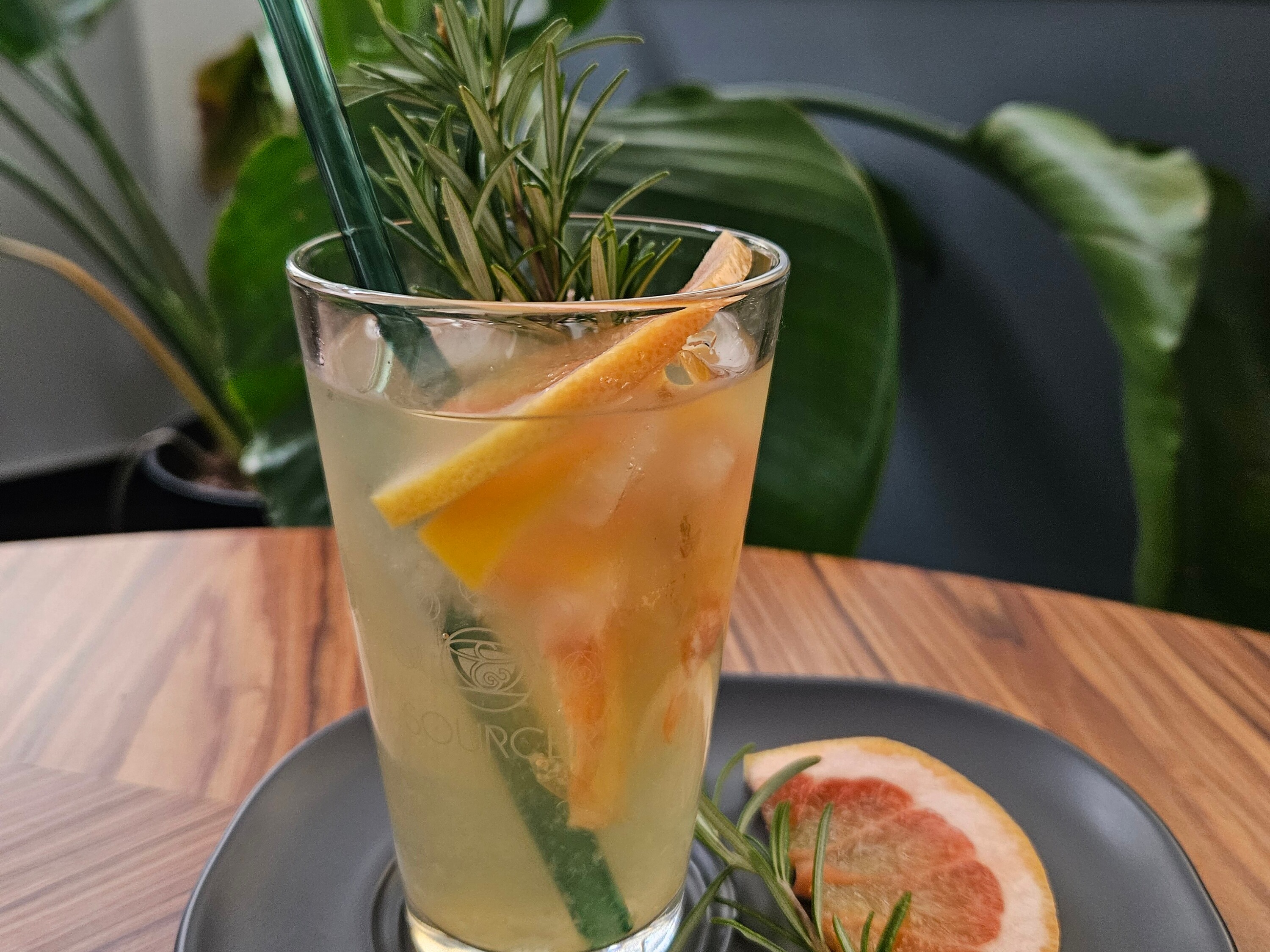 Ein Glas Getränk mit Strohhalm und einer Grapefruitscheibe auf einem Teller.