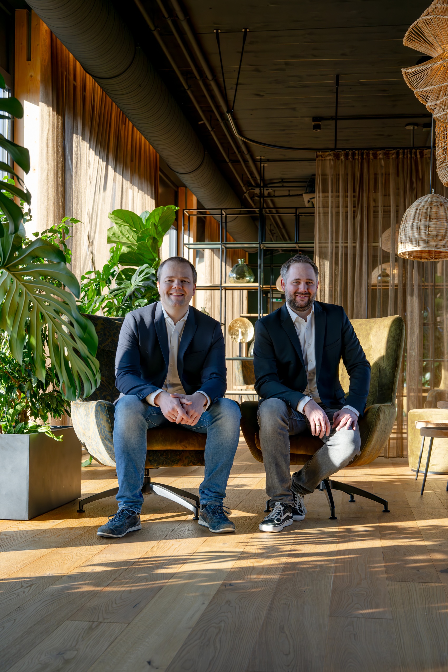 Benjamin und Nikolaus Brandl Zwei Männer sitzen in bequemen Sesseln und lächeln freundlich.