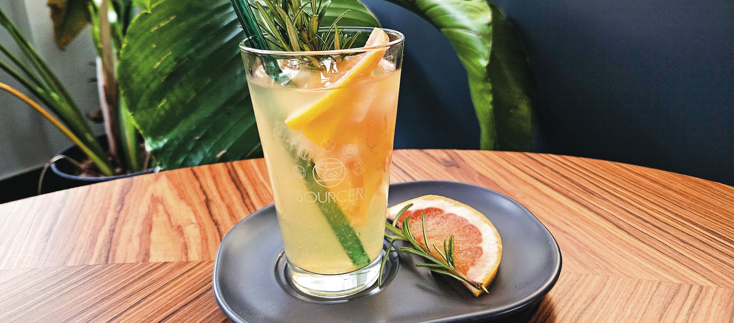 Ein Glas Getränk mit einem Strohhalm und einer Orangenscheibe auf einem Teller.