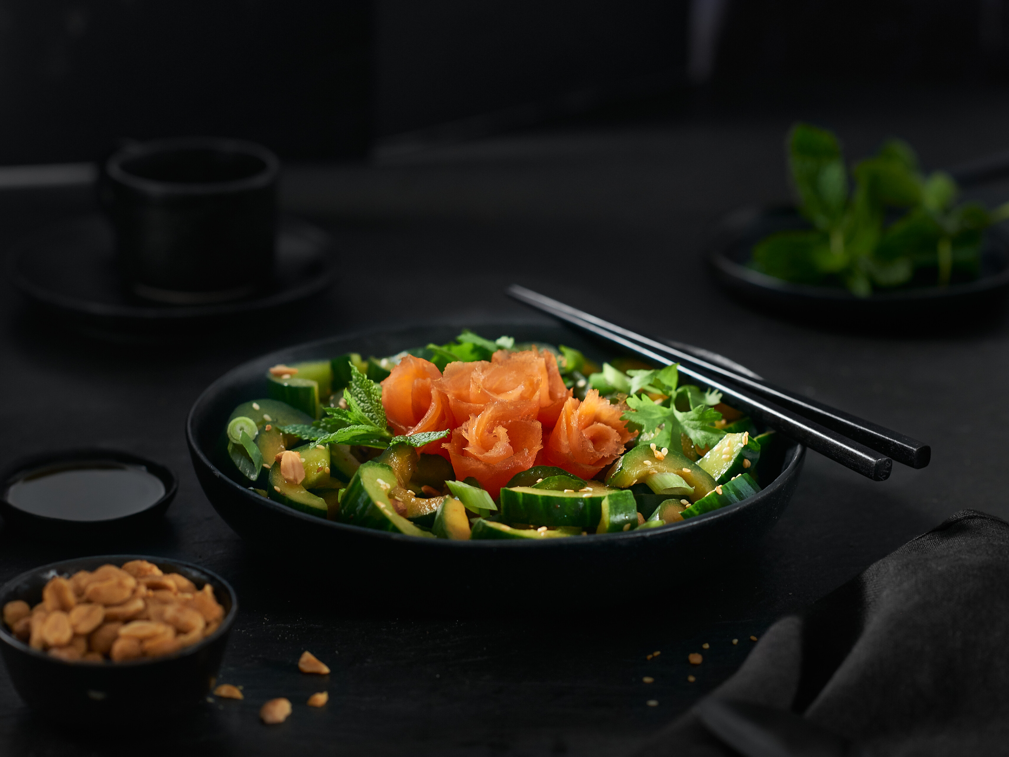 Asiatischer Gurkensalat mit Räucherlachs Eine Schale mit Gurkensalat und Lachs Essstäbchen Erdnüssen und Sojasauce