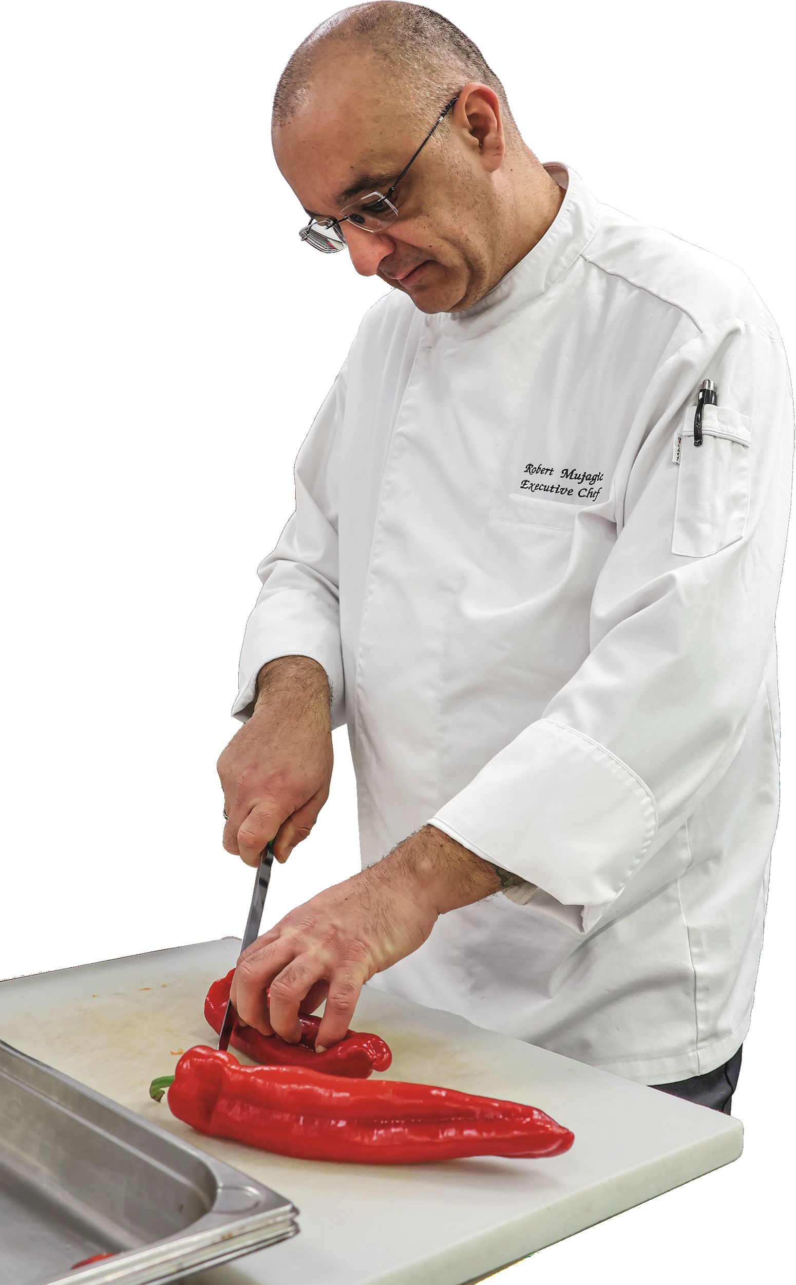 Robert Mujagic, Küchenchef im MOA Berlin Ein Mann im Kochoutfit schneidet eine Tomate.